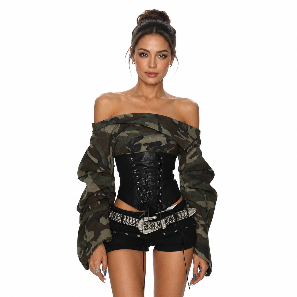 A woman modeling an off-the-shoulder long-sleeve top in a green camouflage pattern, paired with a black lace-up corset, black shorts, and a studded silver belt against a solid white background.